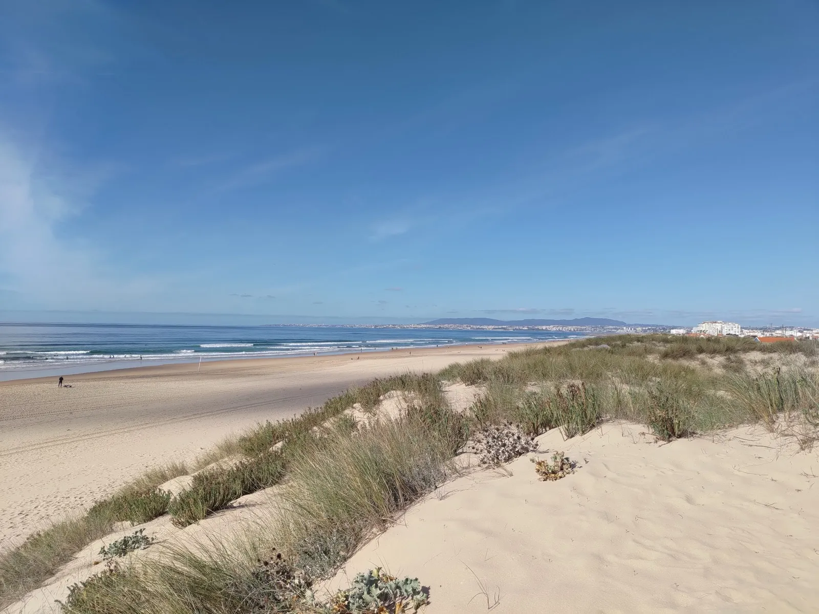 Costa da Caparica beach near Lisbon, with Lisbon visible across the Tagus estuary in the distance
